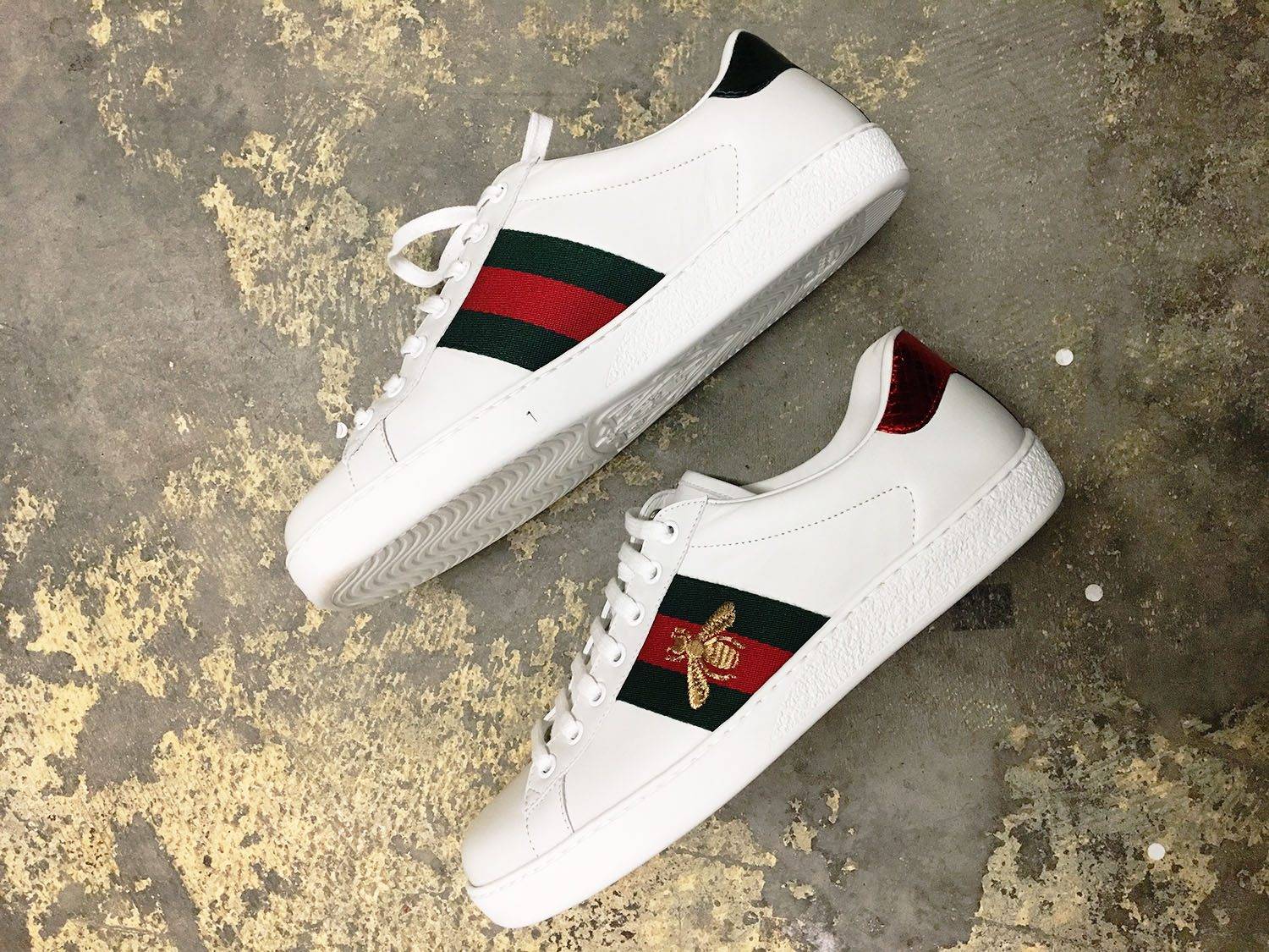 A bird eye view of the Gucci Bee Ace sneaker in new condition on a cement floor of a luxury store, Gucci Ace Bee sneaker Review